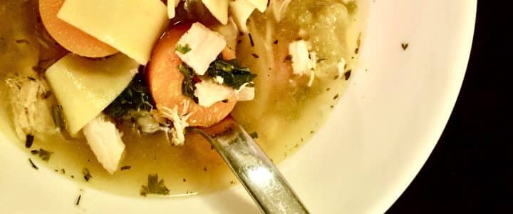 Soupe (soupe poulet, nouilles, carottes et herbes dans un bol avec une cuiller).
