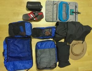 Valise minimaliste : cubes de paquetage, vêtements de voyage et trousse de toilette.