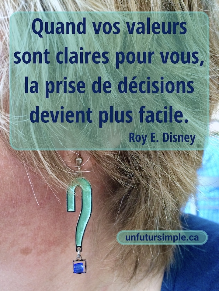 Gros plan sur une boucle-d ’oreille verte et bleu en forme de point d’interrogation portée par une femme blonde avec un t-shirt bleu; citation de Roy E. Disney : Quand vos valeurs sont claires pour vous, la prise de décisions devient plus facile.