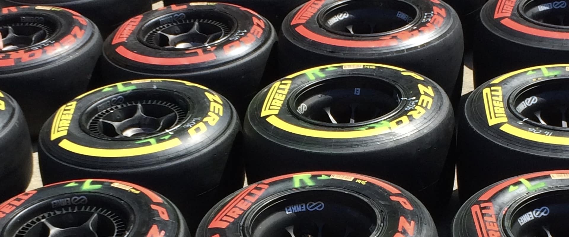 Plusieurs pneus de voitures de course avec lignes jaune et rouge, couchés au sol