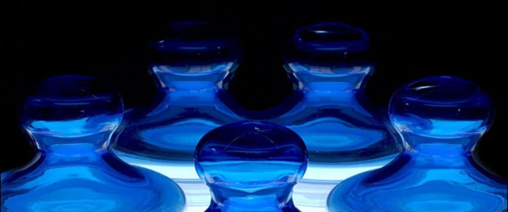 Pions de verre bleu regroupés sur une surface blanche illuminée