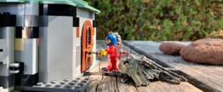 Figurine Lego porte-clés attachée à un trousseau de clés ouvrant la porte d’une maison Lego