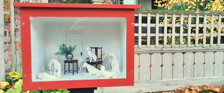 Petite vitrine avec animaux sculptés, à l'extérieur devant une clôture
