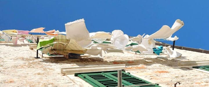 Vêtements qui flottent au vent sur le mur d’une maison sous un ciel bleu.