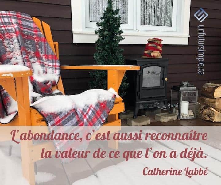 Citation de Catherine Labbé: L'abondance, c'est aussi reconnaître la valeur de ce qu'on a déjà. Scène de Noël sur un perron: chaise, feu, couverture, neige, arbre.