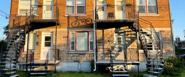 Maison duplex à deux étages avec l’ombre d’un vélo qui semble descendre sur la façade.
