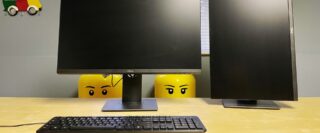 Deux écrans et un clavier sur une table de travail avec des yeux de bonhommes Lego qui regardent.