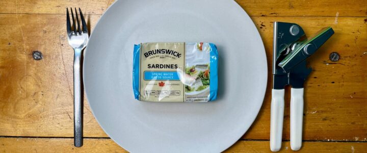 boîte de sardines dans une assiette avec une fourchette et un ouvre-boîte