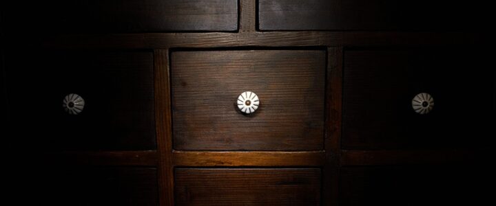 Tiroirs (devanture d’une commode en bois brun avec huit tiroirs munis de poignées rondes blanches.)