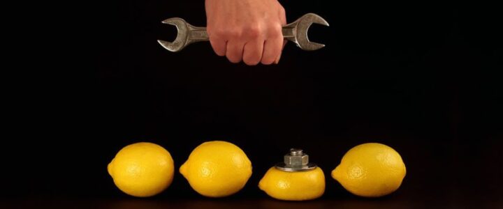 Main tenant une clé au-dessus de 4 citrons dont un avec un boulon.