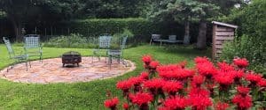 Cour arrière aménagée avec un cercle de feu et monardes en avant plan